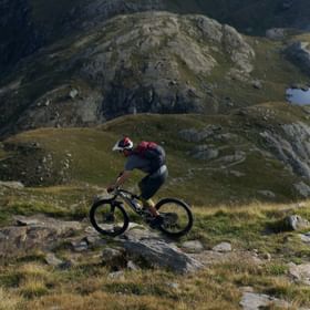 Ein Mountainbiker navigiert geschickt durch steinige Passagen und schmale Pfade in den Bergen von Zermatt.