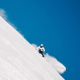 Ein Skifahrer in Zermatt bewältigt eine steile Abfahrt und genießt die klare Bergluft und das Panorama der schweizerischen Alpen.