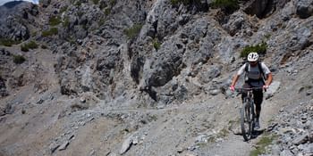 Herausforderung pur: Ein Mountainbiker kämpft sich über steinige Pfade in Zermatt, umgeben von der rauen Schönheit der Alpen.