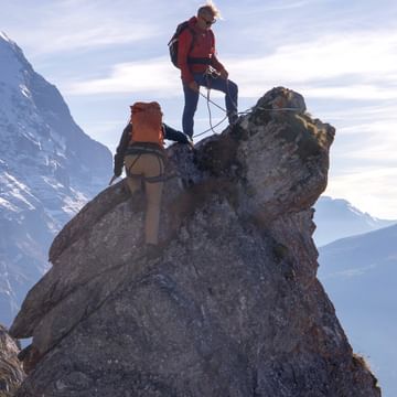 Auf einem felsigen Bergpfad in Zermatt schreiten Wanderer mutig voran, umgeben von der rauen und wilden Natur der Alpen.