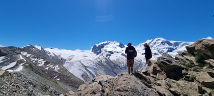 Bergwanderer geniessen die klare Luft und den beeindruckenden Ausblick auf schneebedeckte Gipfel während ihrer Tour in Zermatt.
