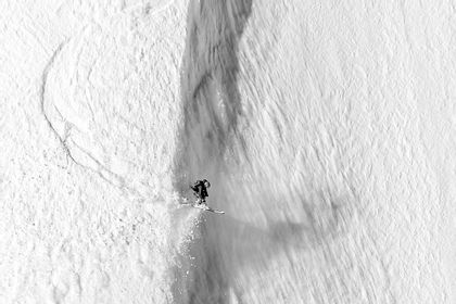 Ein Skifahrer stürzt sich wagemutig eine steile Abfahrt in Zermatt hinunter, umgeben von tief verschneiten Hängen.