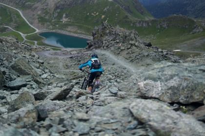 Herausforderung pur: Ein Mountainbiker kämpft sich über steinige Pfade in Zermatt, umgeben von der rauen Schönheit der Alpen.